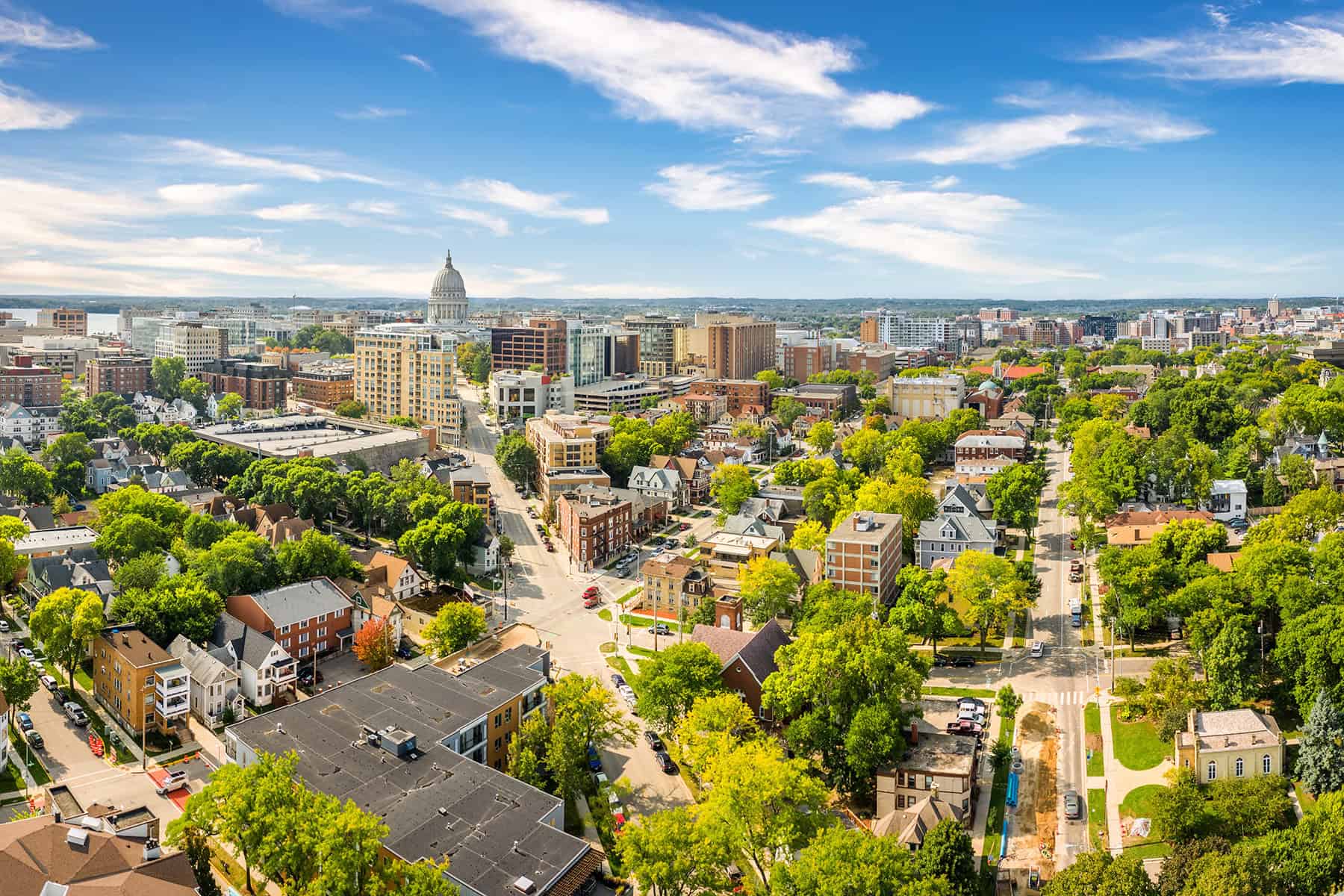 Aerial image of a city with historic architecture, green parks, and clear skies, highlighting urban living and community spaces.