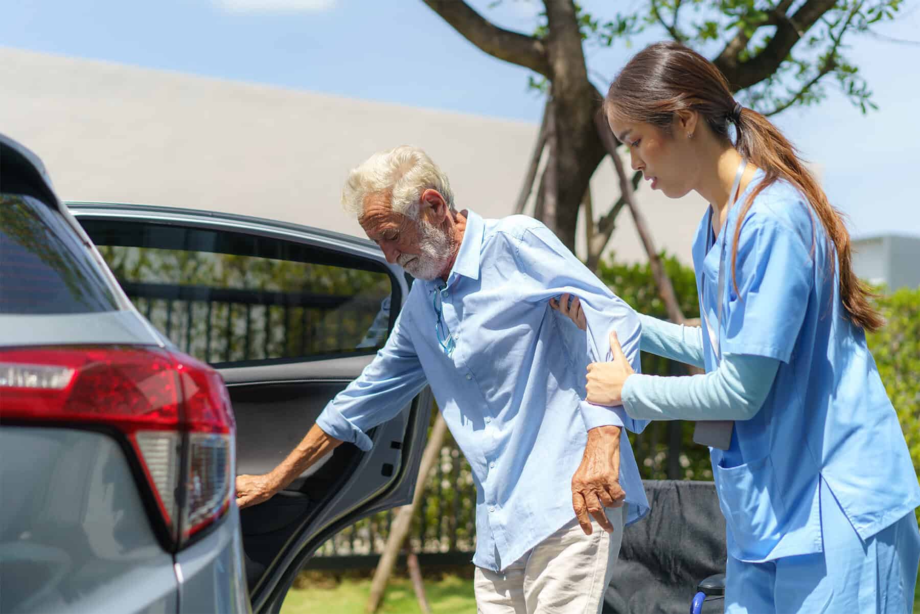 Compassionate home health care provider assisting elderly man with mobility support outdoors, emphasizing quality senior care and home health services.
